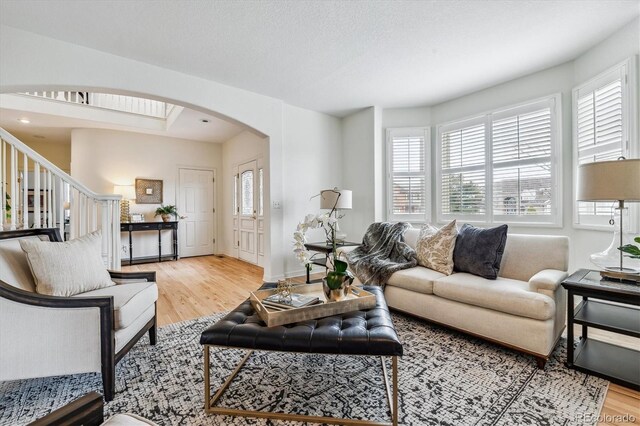 living room featuring arched walkways, wood finished floors, and stairs