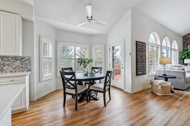 dining room with lofted ceiling, baseboards, a ceiling fan, and light wood-style floors