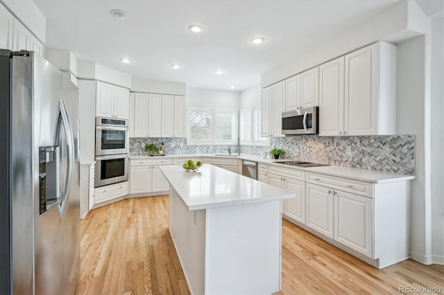 kitchen featuring a center island, light countertops, appliances with stainless steel finishes, light wood-type flooring, and decorative backsplash