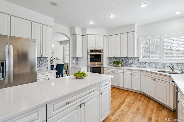 kitchen featuring stainless steel appliances, a sink, white cabinets, and a healthy amount of sunlight