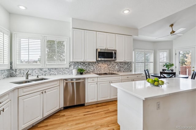 kitchen featuring light wood-style flooring, a sink, stainless steel appliances, light countertops, and backsplash