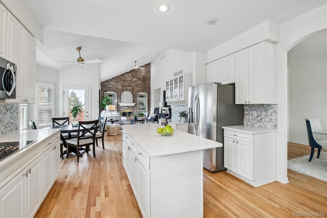 kitchen featuring stainless steel fridge, a fireplace, light wood finished floors, and white cabinetry