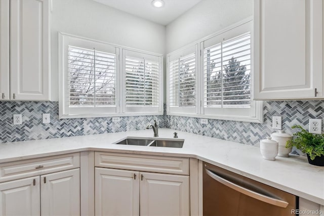 kitchen featuring a sink, white cabinets, backsplash, light stone countertops, and dishwasher