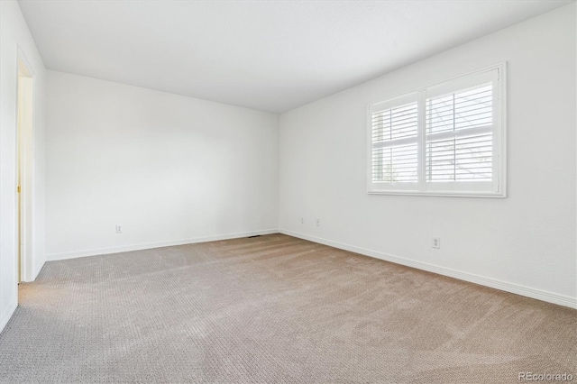 carpeted empty room featuring baseboards