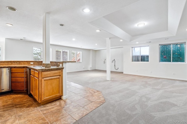 interior space featuring recessed lighting, a raised ceiling, light colored carpet, open floor plan, and dark stone countertops