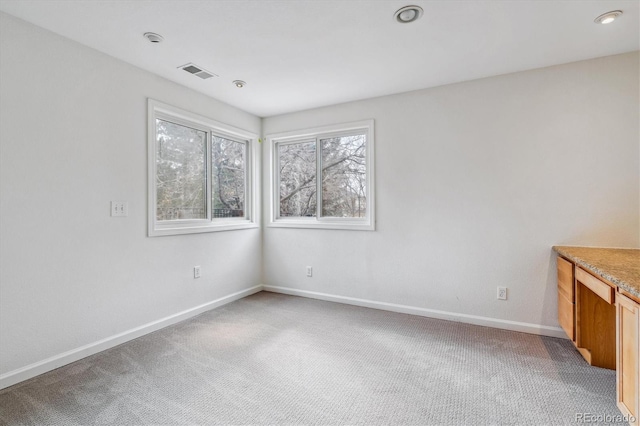 spare room featuring baseboards, visible vents, and light colored carpet