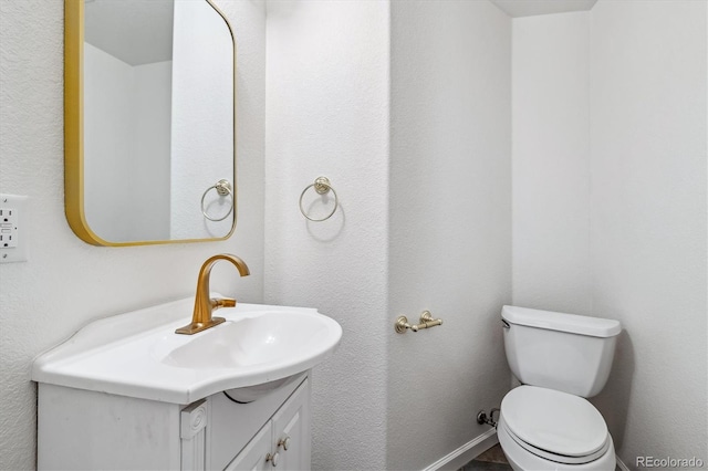 bathroom with baseboards, vanity, and toilet