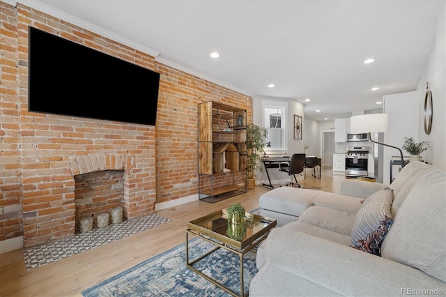 living room featuring brick wall, a brick fireplace, and light hardwood / wood-style flooring