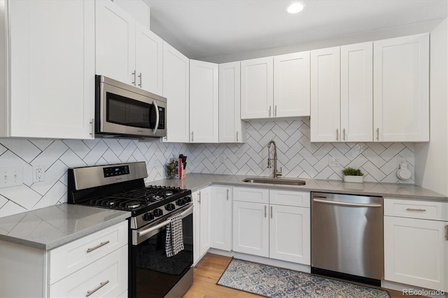 kitchen featuring white cabinetry, sink, light hardwood / wood-style floors, and appliances with stainless steel finishes