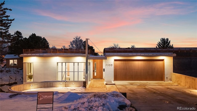 modern home featuring stucco siding, an attached garage, and driveway