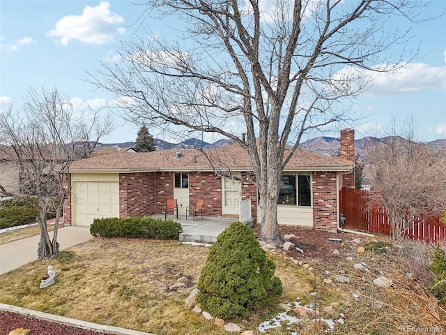 ranch-style house featuring a garage, a front yard, a mountain view, and a patio area