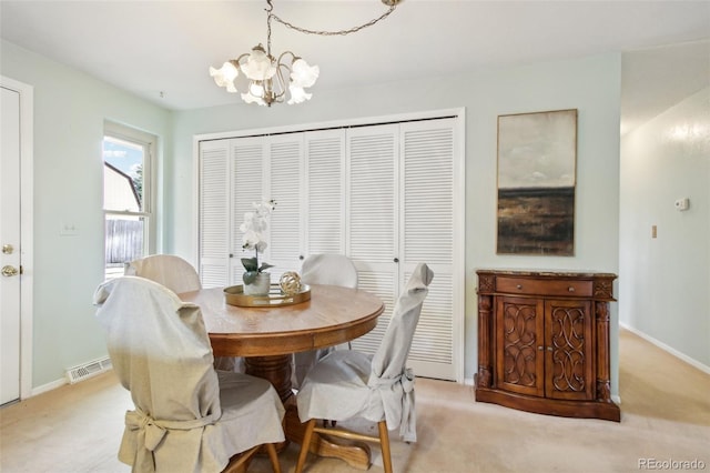 dining area with light carpet and a chandelier