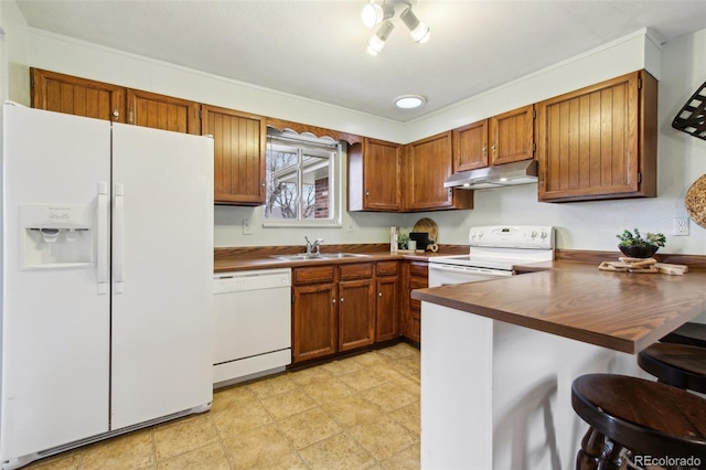 kitchen featuring a kitchen breakfast bar, kitchen peninsula, sink, and white appliances