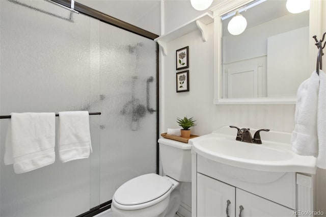 bathroom with a shower with shower door, toilet, and vanity