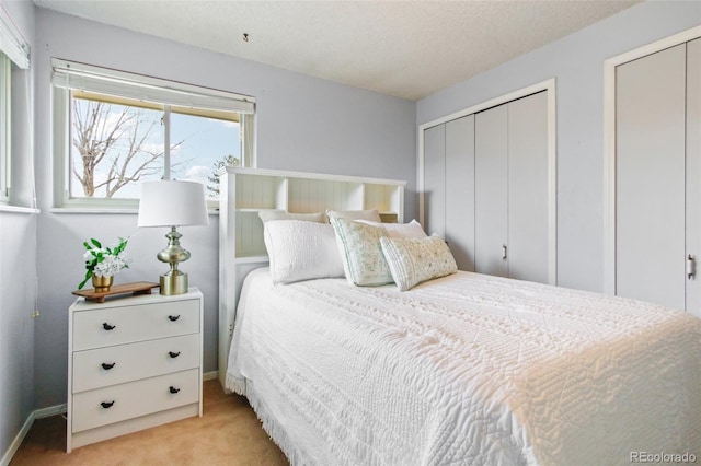 carpeted bedroom featuring two closets and a textured ceiling