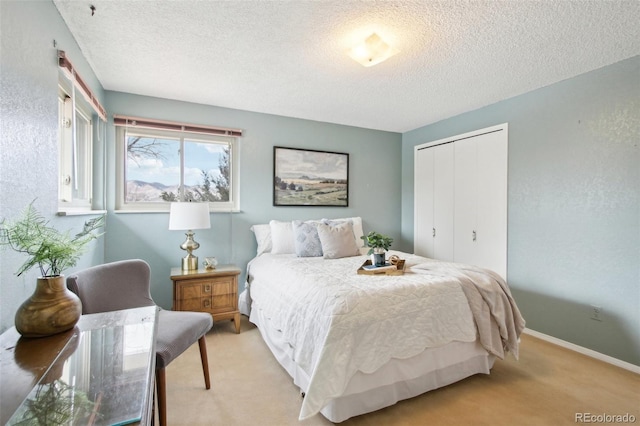 carpeted bedroom with a textured ceiling and a closet