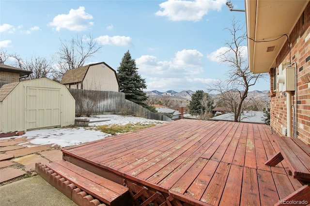 snow covered deck with a storage shed and a mountain view