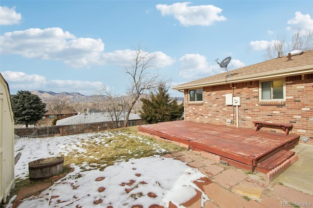 yard layered in snow featuring a deck with mountain view