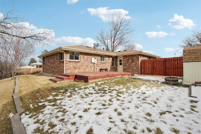 snow covered back of property featuring a deck and a fire pit