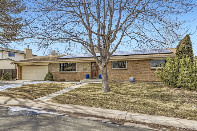 view of front of property featuring a garage, a front yard, and solar panels