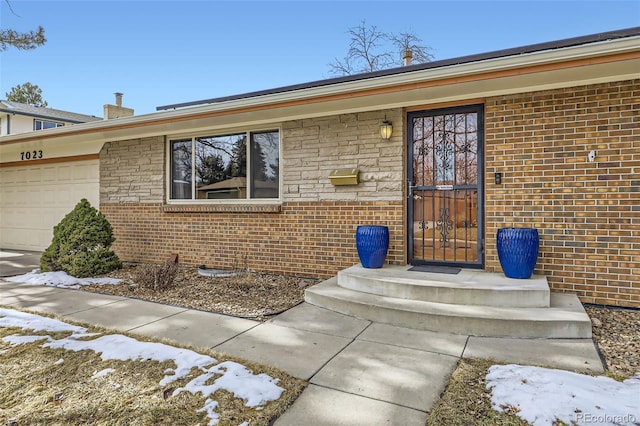 snow covered property entrance featuring a garage