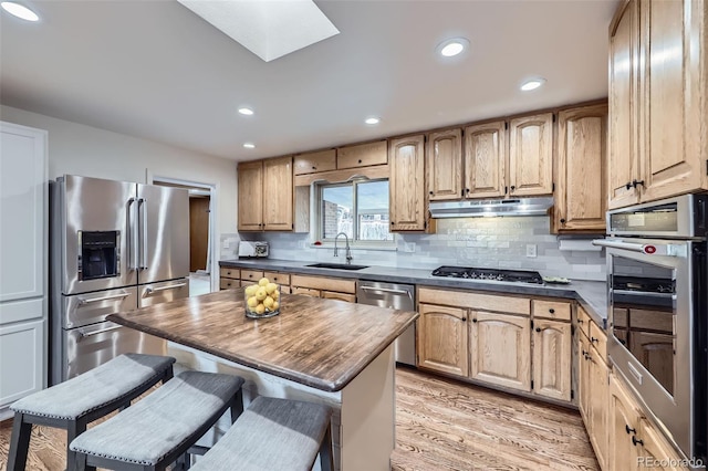 kitchen featuring sink, a breakfast bar area, appliances with stainless steel finishes, a skylight, and a kitchen island