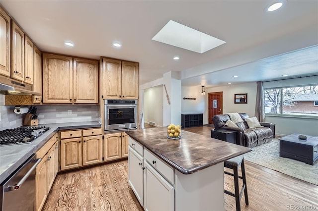 kitchen featuring tasteful backsplash, stainless steel appliances, a skylight, and light wood-type flooring