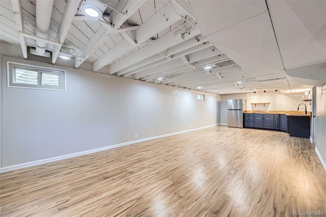 basement featuring stainless steel fridge and light wood-type flooring