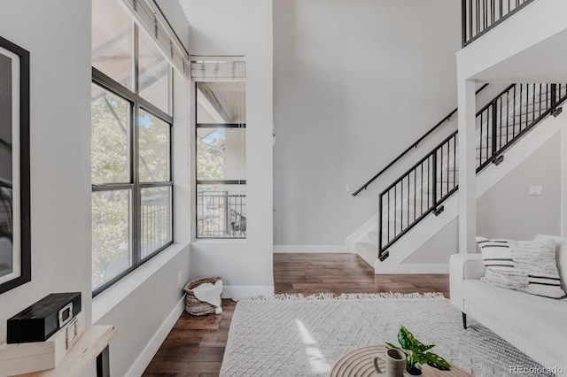 entryway featuring a towering ceiling, stairway, baseboards, and wood finished floors