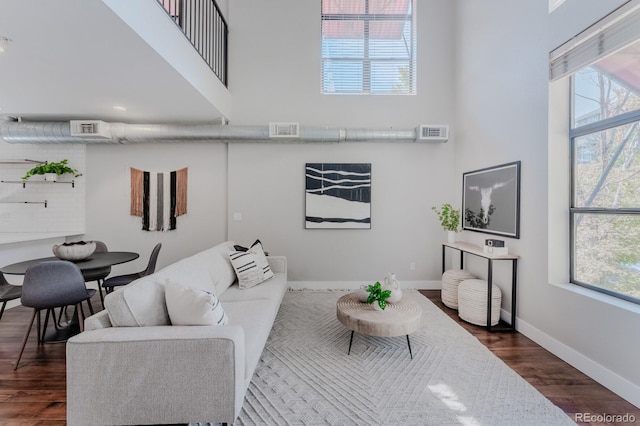 living room featuring a towering ceiling, visible vents, and dark wood-style flooring