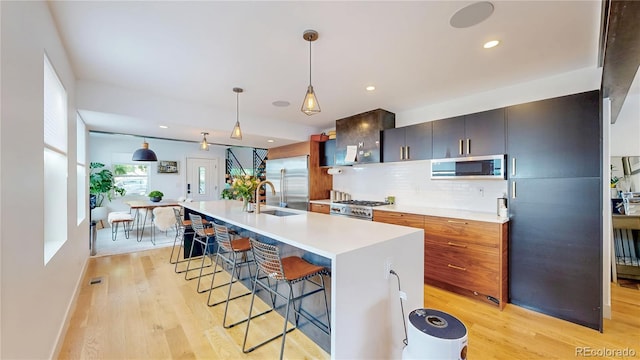 2147 S Sherman St, Denver, CO 80210 - kitchen featuring appliances with stainless steel finishes, light wood-style flooring, a breakfast bar area, light countertops, and recessed lighting