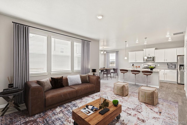 living room with light hardwood / wood-style flooring and a notable chandelier