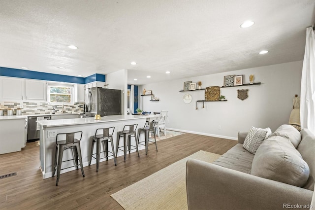 living room featuring sink, a textured ceiling, and hardwood / wood-style floors