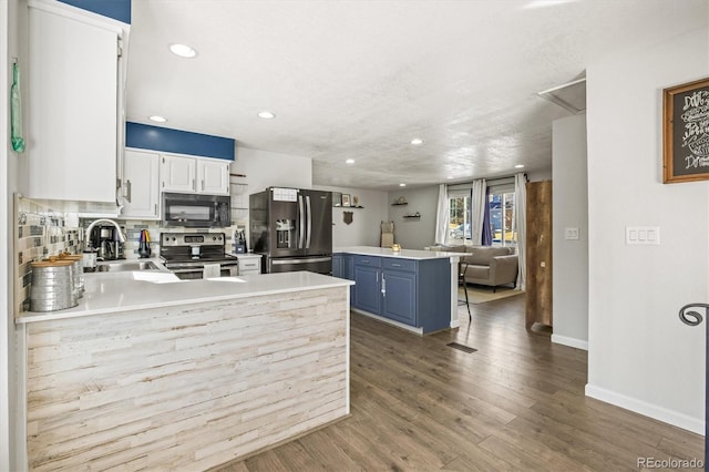 kitchen featuring stainless steel appliances, kitchen peninsula, sink, white cabinetry, and blue cabinets