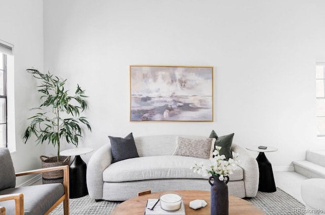 living area with carpet, baseboards, and a healthy amount of sunlight