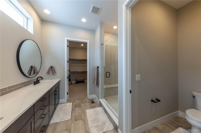 bathroom featuring hardwood / wood-style flooring, toilet, a shower with door, and vanity