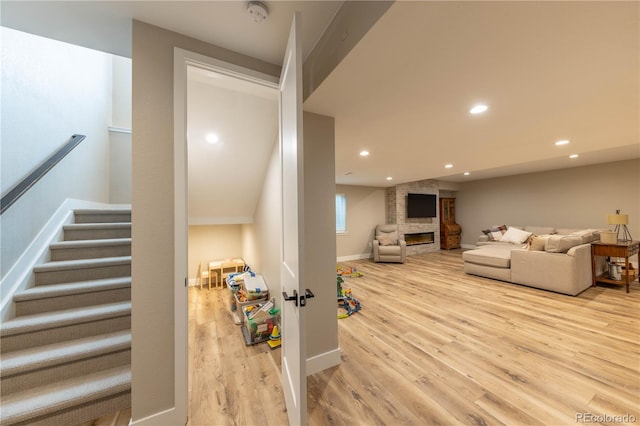 staircase with vaulted ceiling, a stone fireplace, and hardwood / wood-style flooring