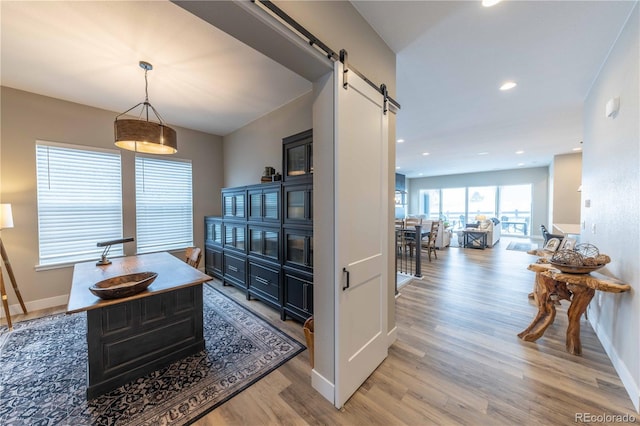 interior space with baseboards, a barn door, recessed lighting, and light wood-style floors