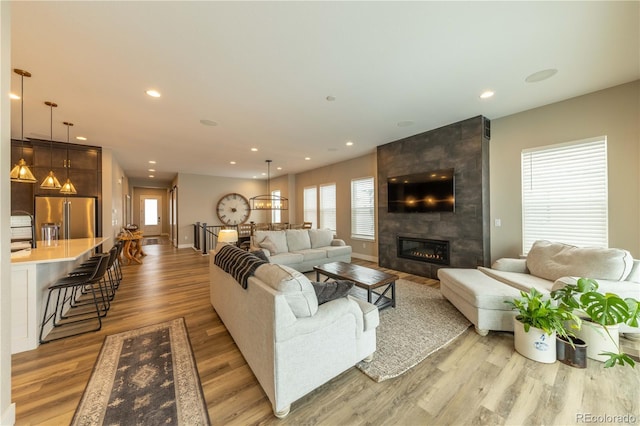 living room featuring recessed lighting, a fireplace, baseboards, and wood finished floors
