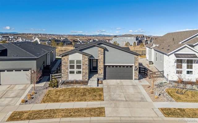 view of front facade featuring an attached garage, concrete driveway, stone siding, and a residential view