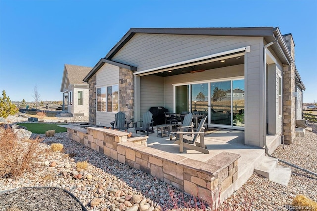 back of house with ceiling fan, stone siding, and a patio area