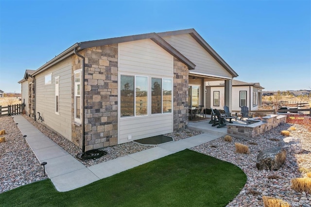 back of property with stone siding, a patio area, and fence