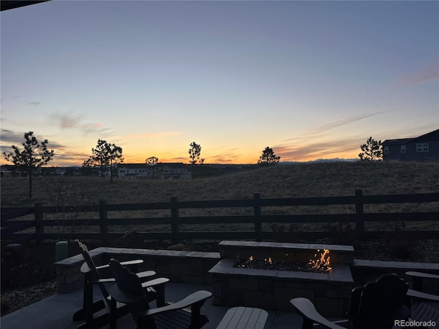 patio terrace at dusk featuring fence and a fire pit
