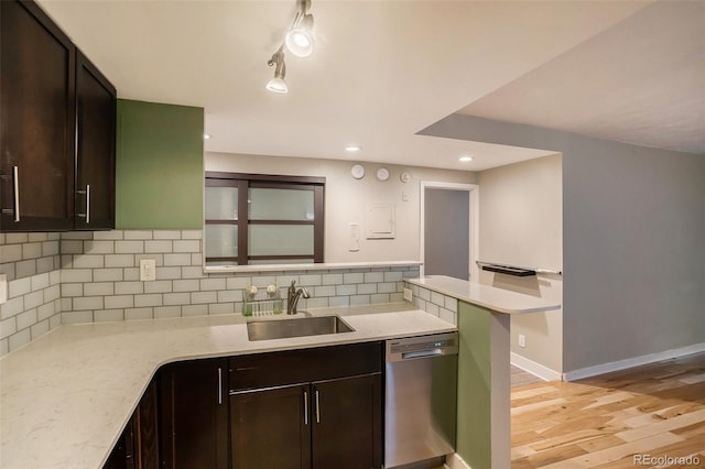 kitchen featuring dishwasher, sink, backsplash, dark brown cabinets, and light hardwood / wood-style flooring