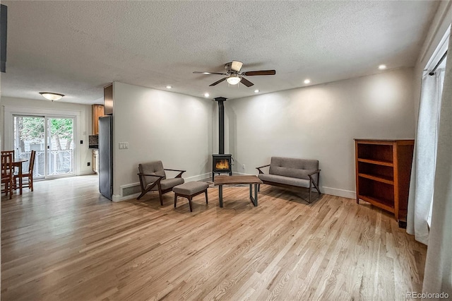 117 Sandler Dr, Lafayette, CO 80026 - sitting room featuring a wood stove, a textured ceiling, light wood finished floors, ceiling fan, and baseboards