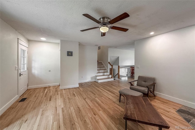 117 Sandler Dr, Lafayette, CO 80026 - living area featuring light wood-style flooring, a ceiling fan, a textured ceiling, baseboards, and stairway