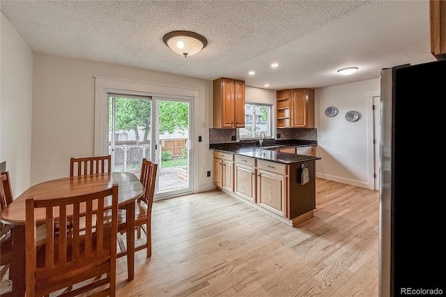 117 Sandler Dr, Lafayette, CO 80026 - kitchen with freestanding refrigerator, dark countertops, open shelves, light wood-style flooring, and a peninsula