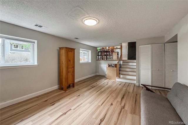 117 Sandler Dr, Lafayette, CO 80026 - unfurnished living room featuring wood finished floors, baseboards, a textured ceiling, and stairs
