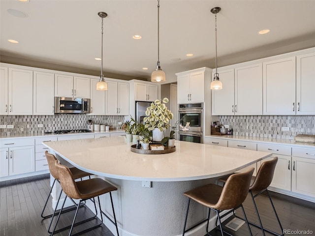 11096 Endeavor Dr, Parker, CO 80134 - kitchen with appliances with stainless steel finishes, a kitchen island, backsplash, a kitchen bar, and white cabinetry