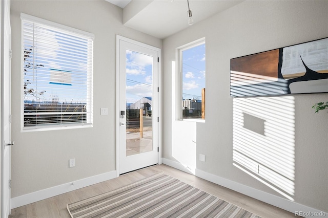 doorway to outside with baseboards, a healthy amount of sunlight, and wood finished floors